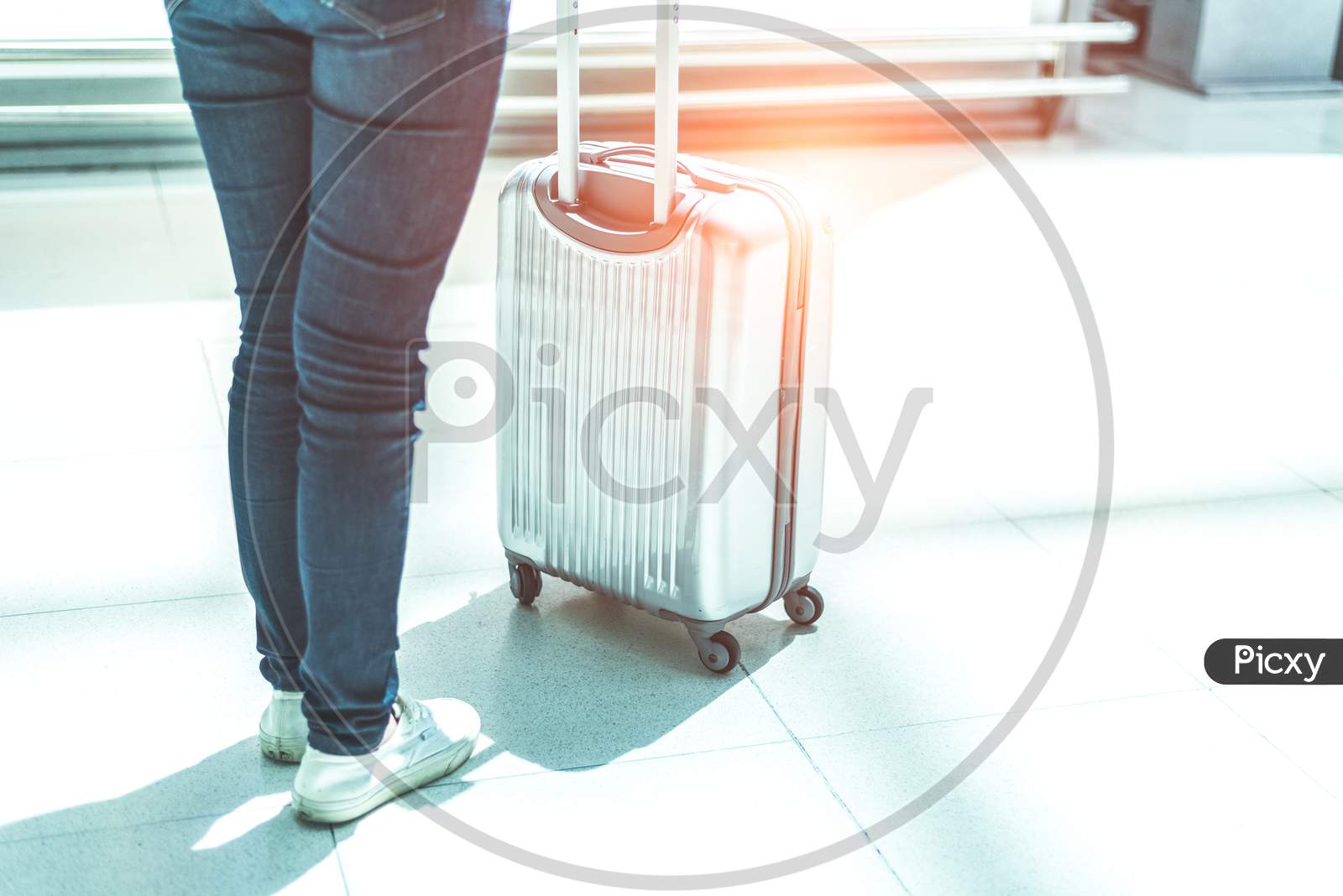 Close Up Woman And Suitcase Trolley Luggage In Airport. People And Lifestyles Concept. Travel And Business Trip Theme. Woman Wearing Jeans Going On Tour And Traveling Around The World By Alone.