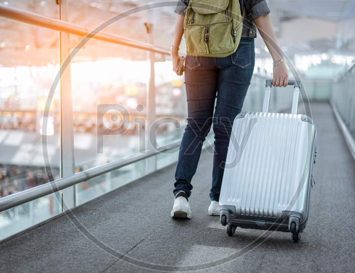 Close Up Lower Body Of Woman Traveler With Luggage Suitcase Going To Around The World By Plane. Female Tourist On Automatic Escalator In Airport Terminal.