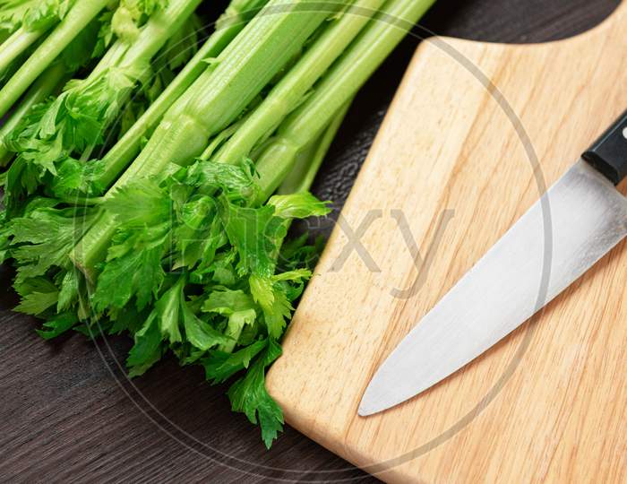 Bunch Of Fresh Celery Stalk On Wooden Table And Cutting Board And Knife With Leaves. Food And Ingredients  Of Healthy Vegetable. Freshness Herbal And Low Calories For Dieting With Plenty Of Vitamin