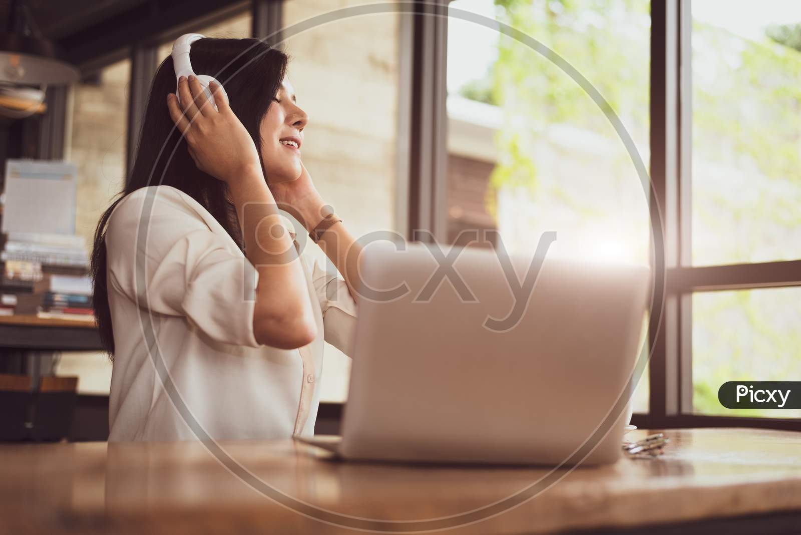 Happy Asian Woman Relaxing And Listening Music In Coffee Shop With Computer Laptop. People And Lifestyles Concept. Freelance And Outdoors Workplace Outdoors Theme.