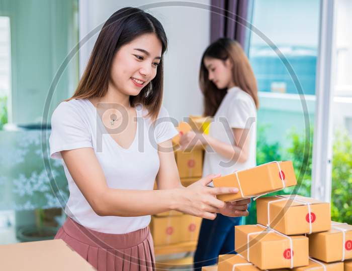 Two Young Asian Girl Freelancers Business Owner Working At Home Office And Sorting Parcel Post Box To Delivery Service To Customer. Packaging Order And Shopping Online Concept.