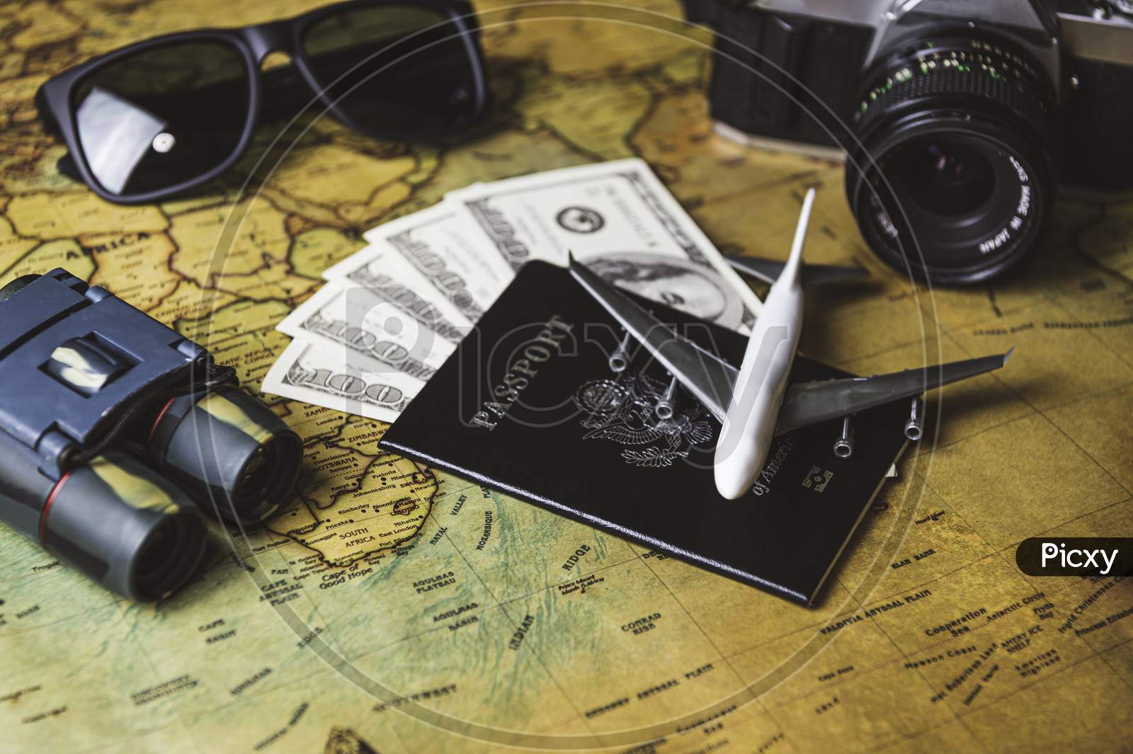 Tourist Planning Props And Travel Accessories With American Passport, Airplane, Digital Camera, Telescope, Sunglasses And Us Dollar Banknote Money On Old Grunge Style Map. Holiday And Vacation Concept