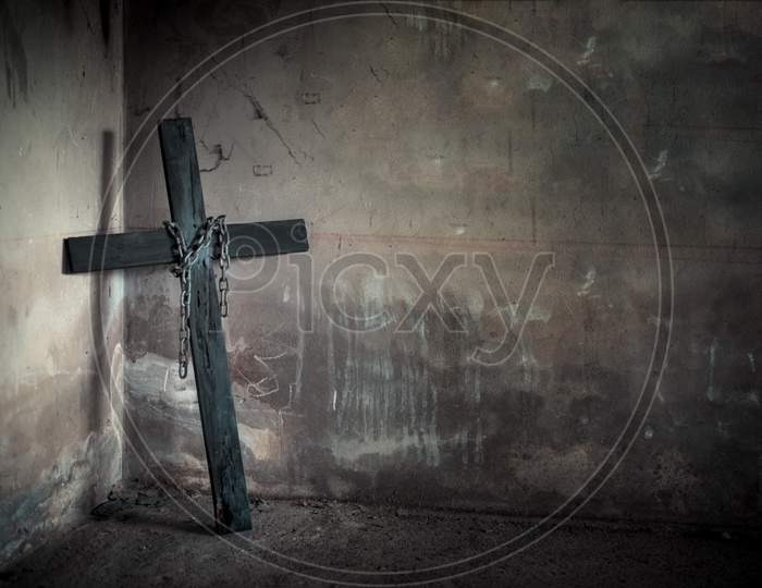Black Cross Against Wall With Hanging Steel Chain And Gun. Halloween Day Party Festival Celebration. Ancient Sign Of Religion. Dark And Scary Tone