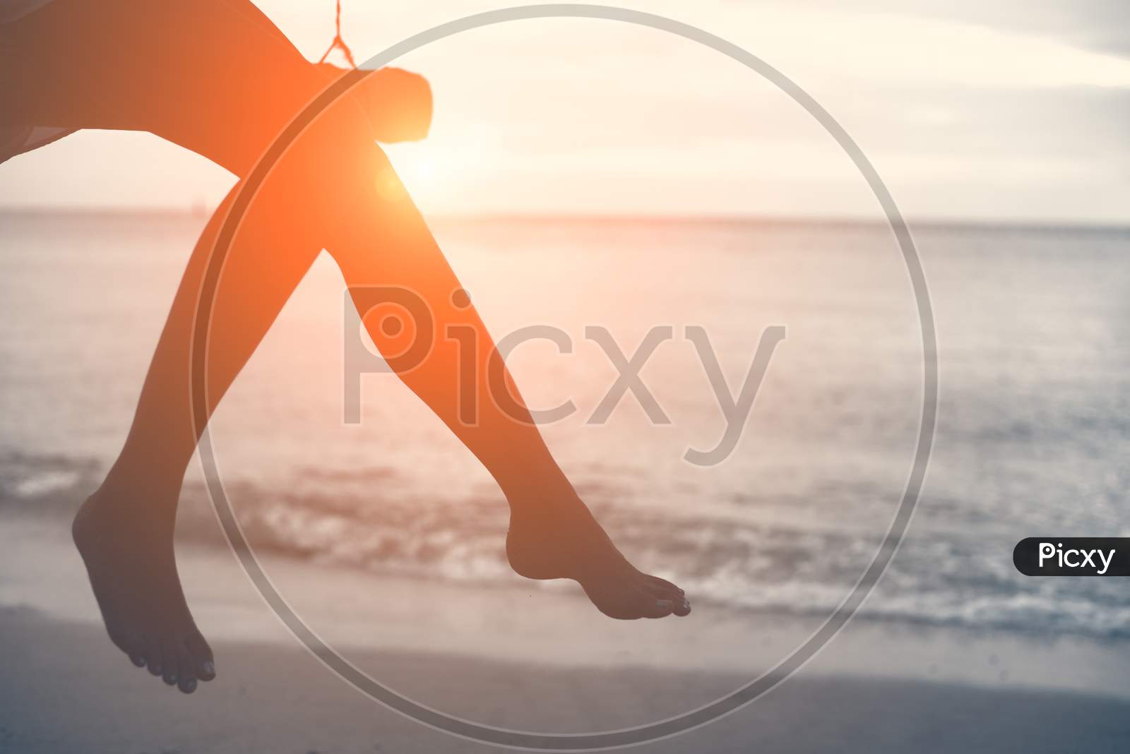 Woman Legs At Beach On Wooden Swing With Sunset. Single Woman Concept. People And Lifestyle Concept. Lonely And Sadness Concept. Beach And Sea Theme. Finding Soulmate Theme. Copy Space On Right