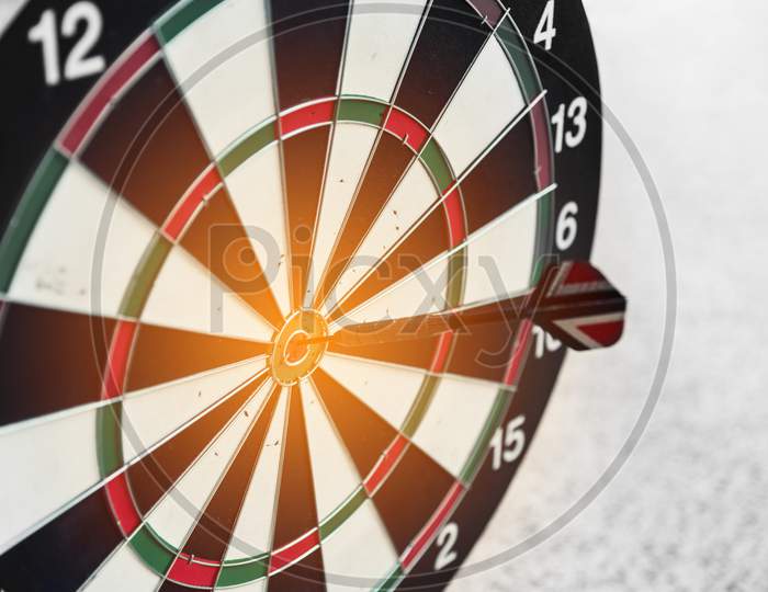 Dart Board And Arrow In Middle. Business And Success Concept. Achievement And Target Theme. Orange Sun Light Effect. High Contrast Tone