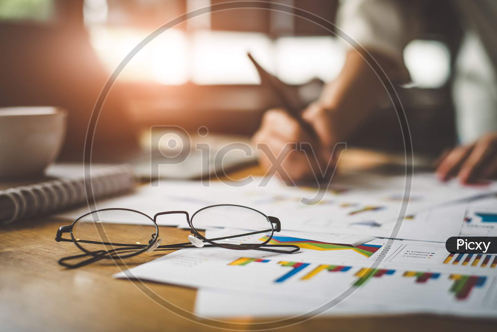 Close Up Of Glasses With Businesswoman  Writing Summary Report Data In Background. Marketing And Business Ownership Concept. People And Lifestyles Concept. Business Employee And Financial Theme.