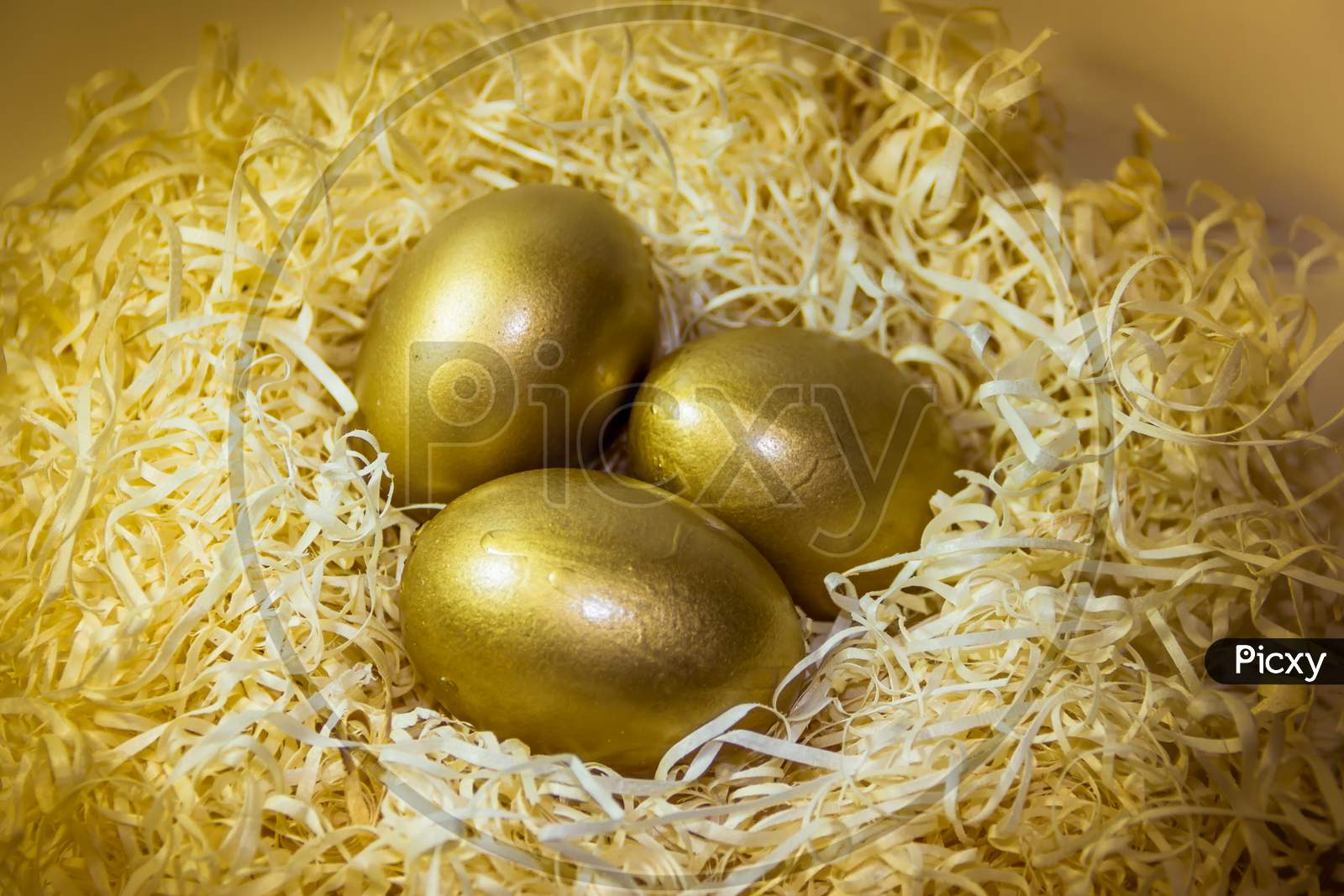 Golden Easter Eggs In Straw Nest With Rustic Wooden Background