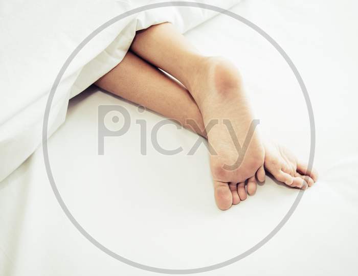 Barefoot Of Human On Bed In Morning. Single And Working People Concept. Lazy Day And Happiness Home Theme.