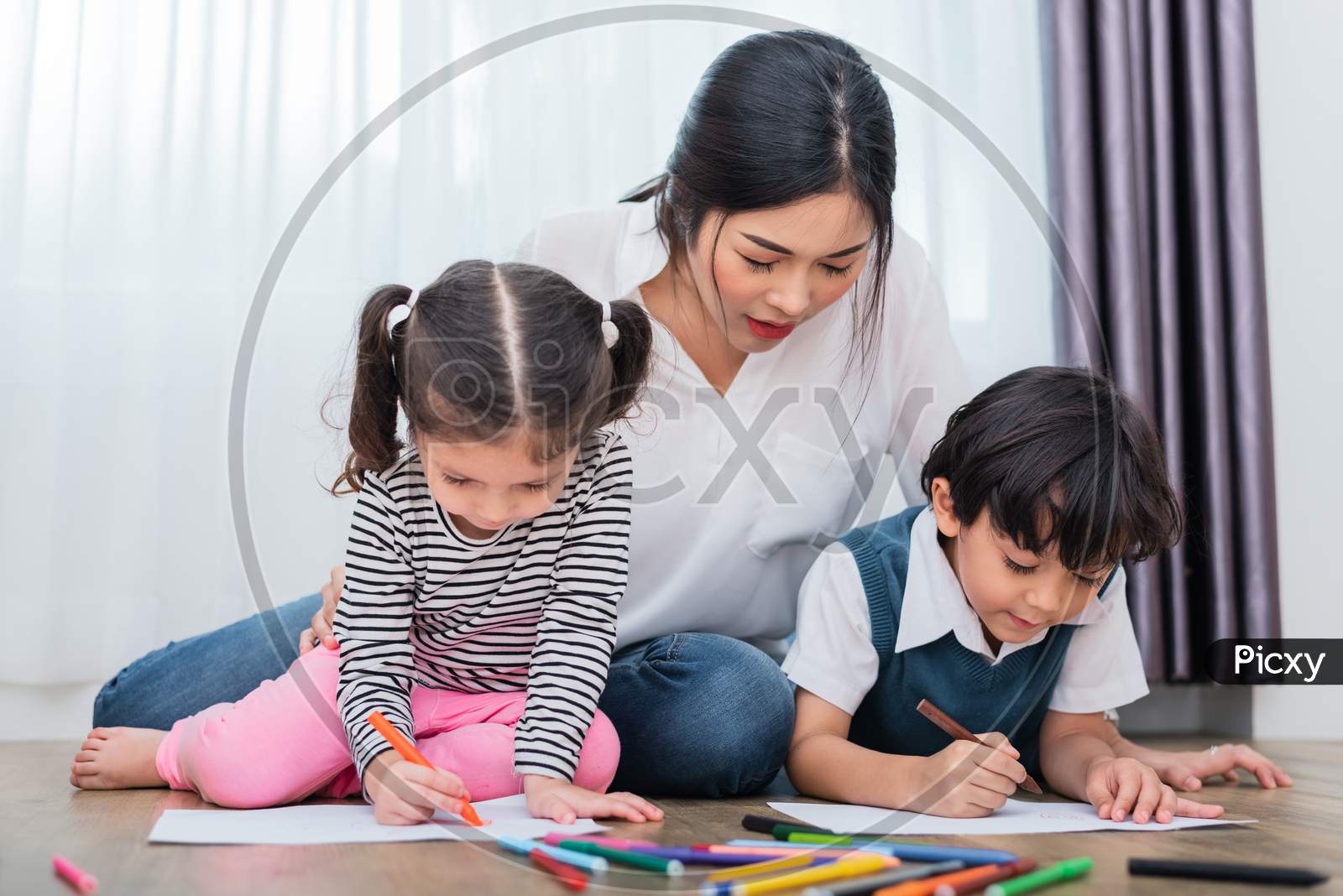 Mother Teaching Children In Drawing Class. Daughter And Son Painting With Colorful Crayon Color In Home. Teacher Training Students In Art Classroom. Education And Learning Development Of Kids Theme.