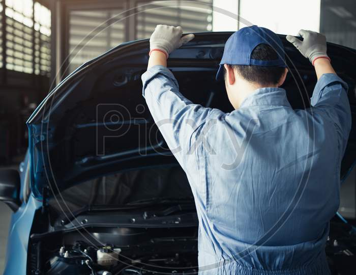 Car Mechanic Opening Car Hood For Internal Checking To Maintenance Vehicle By Customer Claim Order In Auto Repair Shop Garage. Engine Repair Service. People Occupation And Job. Automobile Technician