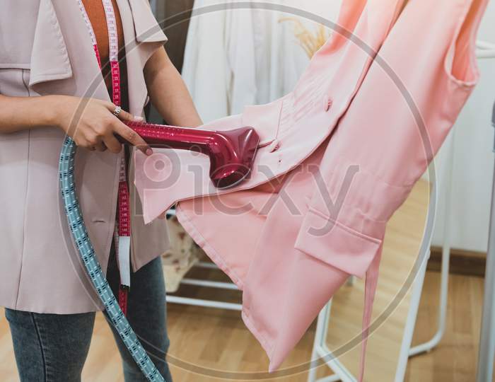 Woman Using Steaming Iron To Ironing Fashion Shirt In Laundry Room. Girl Doing Stream Vapor Iron For Press Clothes In Hand. Launder Concentrate Work And Delivery To Customer. Part Time Job Occupation