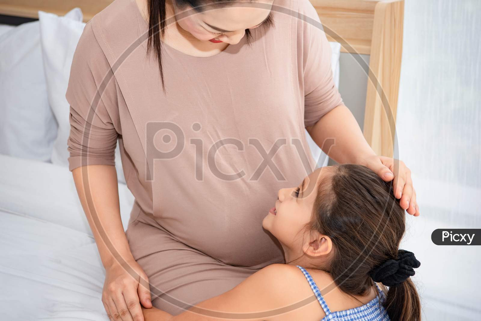 Cute Daughter Hugging Mother And Listening To Voice Of Baby In Mother Belly For Checking And Looking At Mom Face. Pregnant And Parents. Health And Medical. People Lifestyles And Family Love Concept.