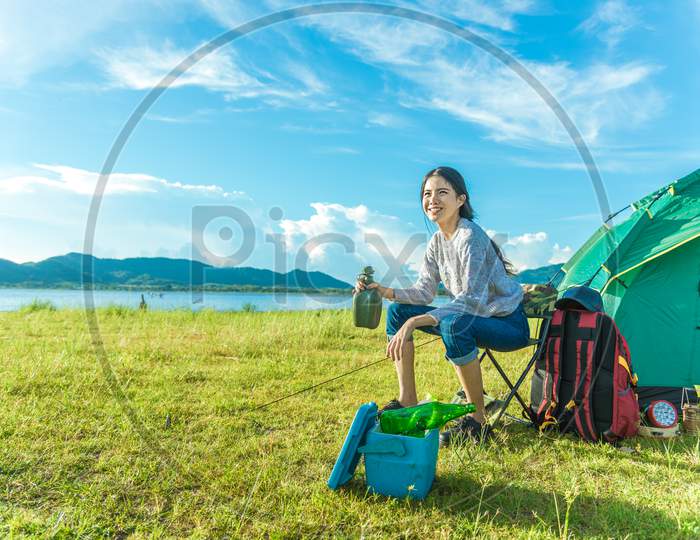 Happy Woman Drinking Alcohol While Camping At Meadow. People And Lifestyles Concept. Travel And Adventure Theme. Female Tourist Portrait