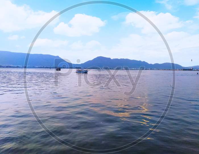 Skyline view of lake, The beautiful scenery of a lake in which a boat sweem and lake is surrounded by a hills in a blue sky and in blue sky some where is white clouds