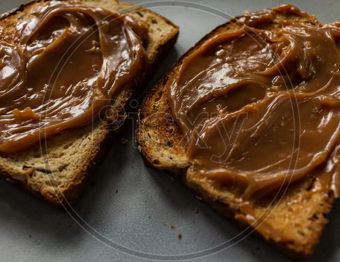 Whole Wheat Toast With Seeds Covered In "Dulce De Leche". Fatty Food For Breakfasts And Snacks.