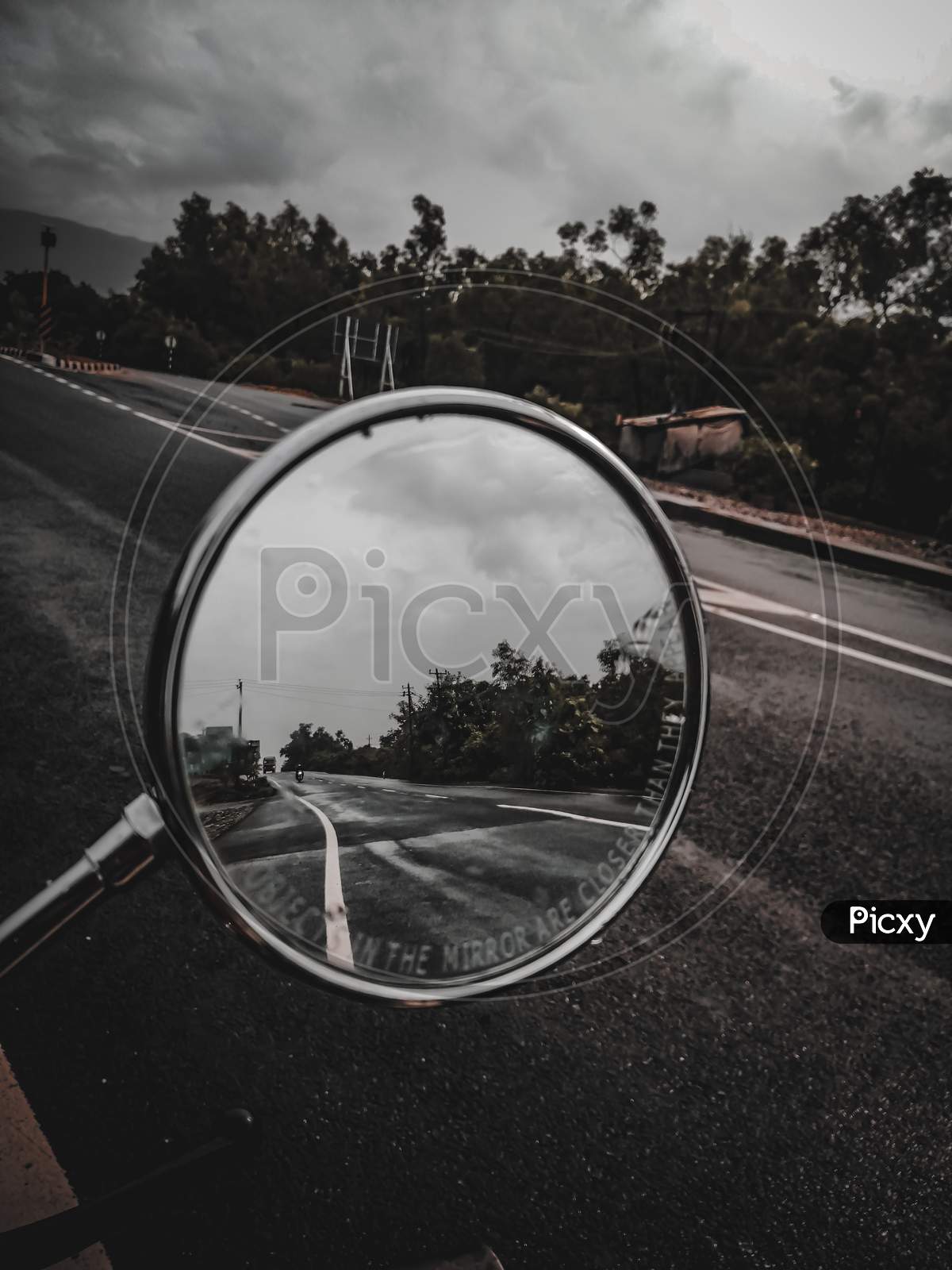 A side mirror that shows moody road