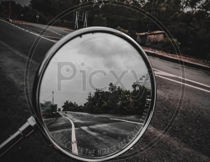 A side mirror that shows moody road