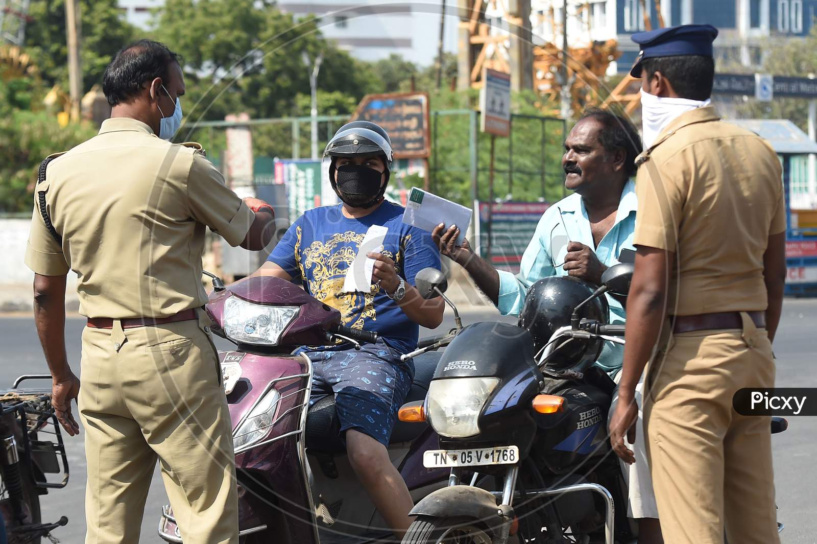 Commuters wait as a police personnel checks for valid travel credentials after a lockdown was reimposed as a preventive measure against the spread of the COVID-19 coronavirus, in Chennai on June 19, 2020.