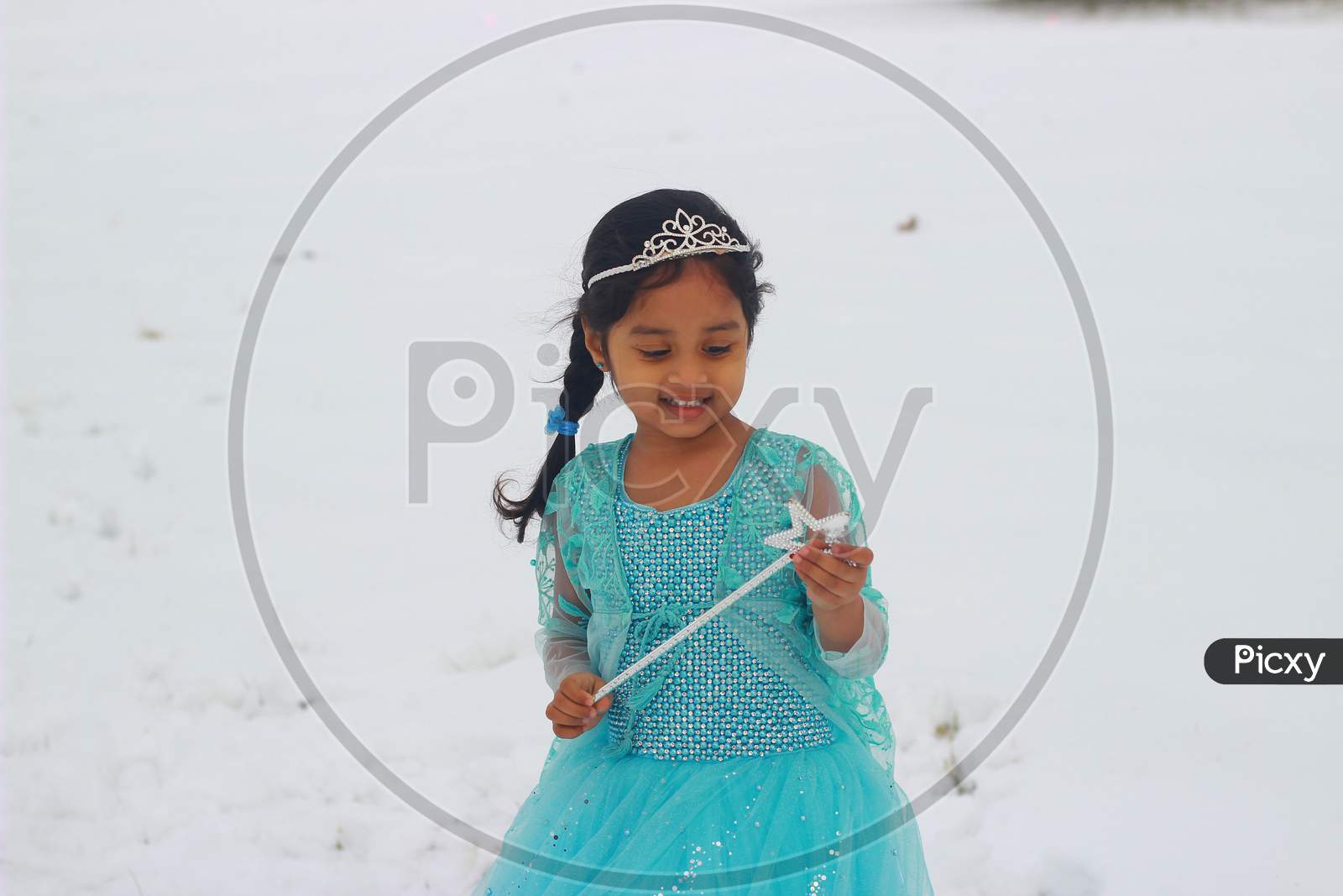 A little girl in a beautiful blue frock playing in the snow