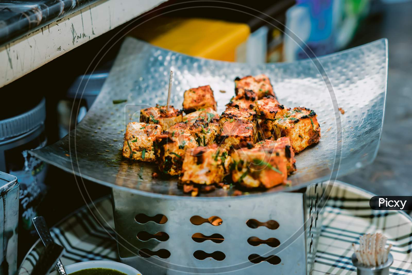 Paneer Tikka Kabab in red sauce - is an Indian dish made from chunks of cottage cheese marinated in spices & grilled in a tandoor. Served in a plate with salad & green mint chutney. Selective focus
