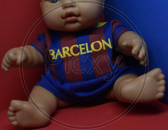 Close Up View Of A Barcelona Fan Base Doll Boy In Blue And Red Jersey In Red And Blue Background.
