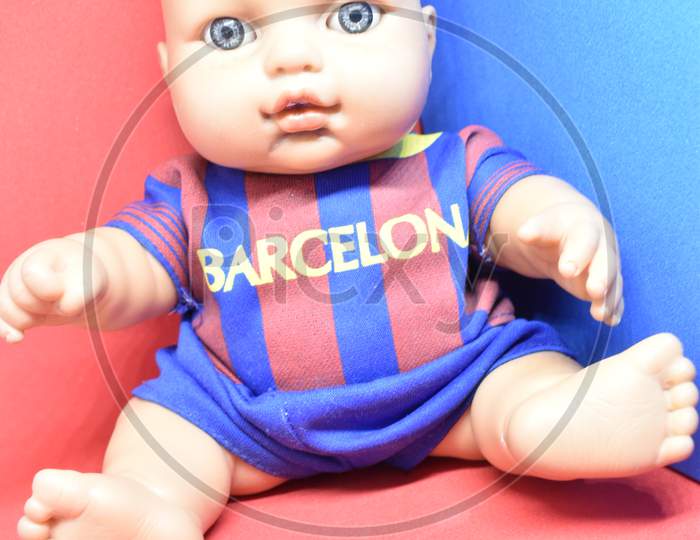 Close Up View Of A Barcelona Fan Base Doll Boy In Blue And Red Jersey In Red And Blue Background.