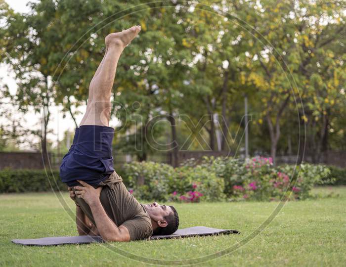Mid-Aged Man Doing Yoga In A Park Covered With Trees