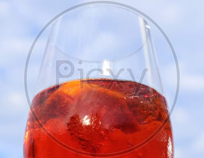 Refreshing orange summer cocktails with cola and ice against a blue sky background. Close up view.