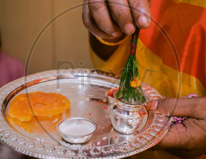 A women holding a bowl of Ganga jal with sweet for her daughter rice feeding ceremony. Its a rituals of traditional Hindu rice ceremony which is known as Ashirwad.