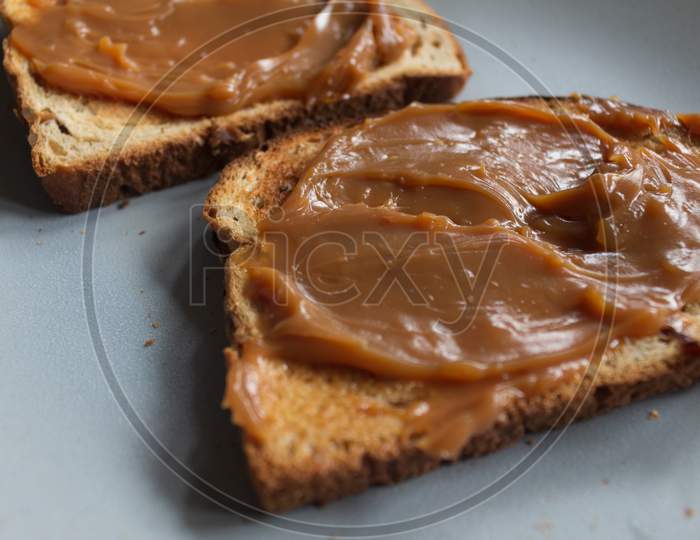 Whole Wheat Toast With Seeds Covered In "Dulce De Leche". Fatty Food For Breakfasts And Snacks.