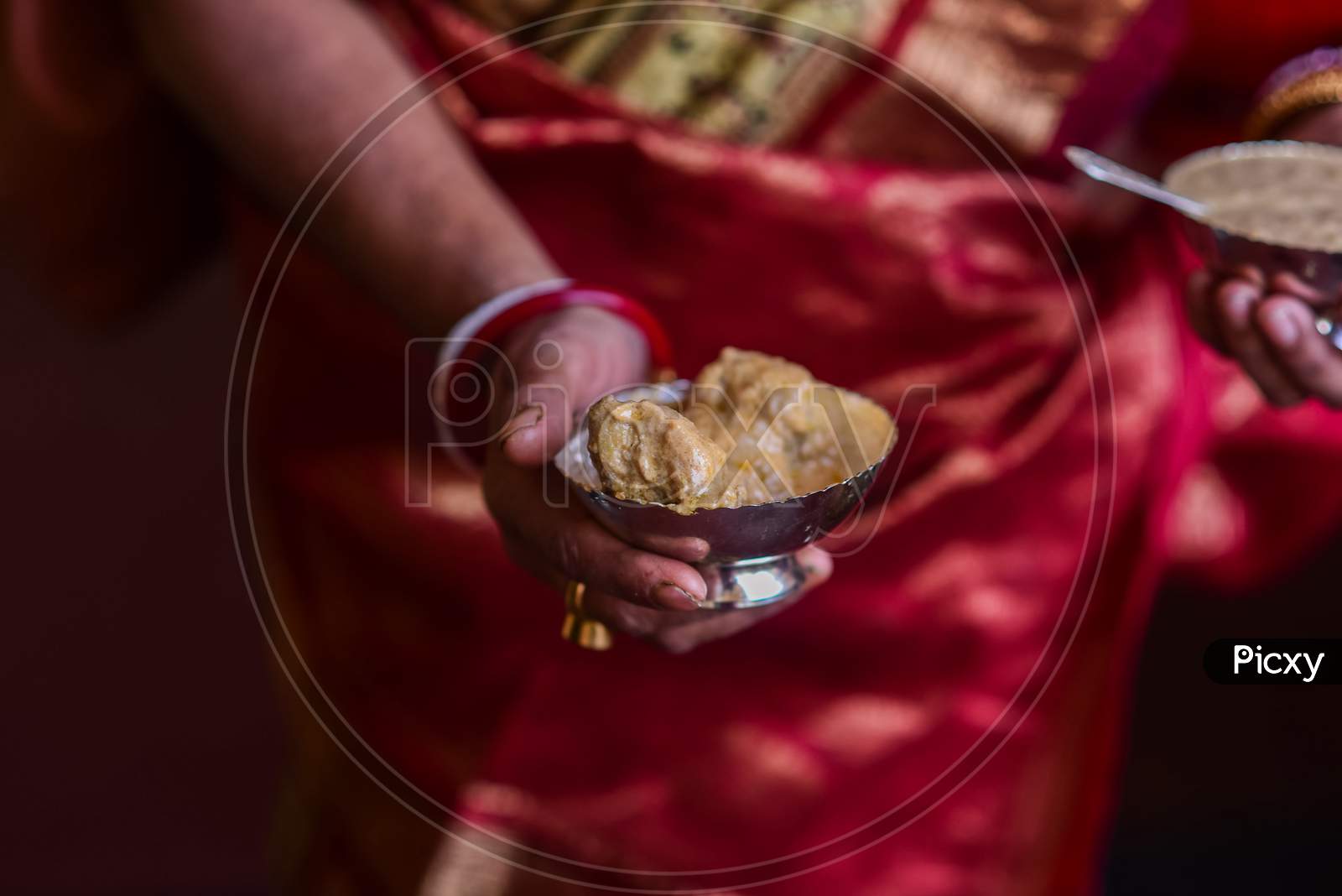 A woman holding a bowl with paes a traditional bengali dish in rice feeding ceremony of child