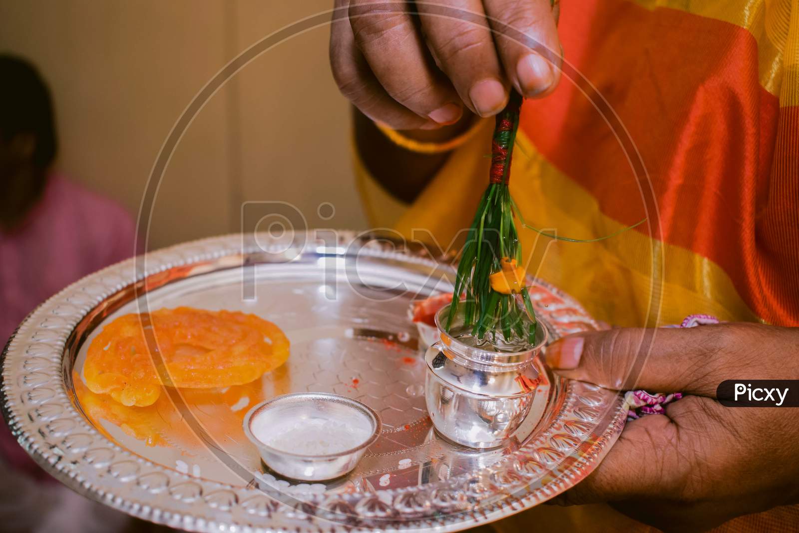 A women holding a bowl of Ganga jal with sweet for her daughter rice feeding ceremony. Its a rituals of traditional Hindu rice ceremony which is known as Ashirwad.