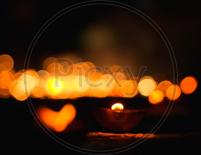 Hindu Festival Of Lights. Clay Diya Candle Illuminated . Traditional Oil Lamp On Dark Bokeh Background, Copy Space.