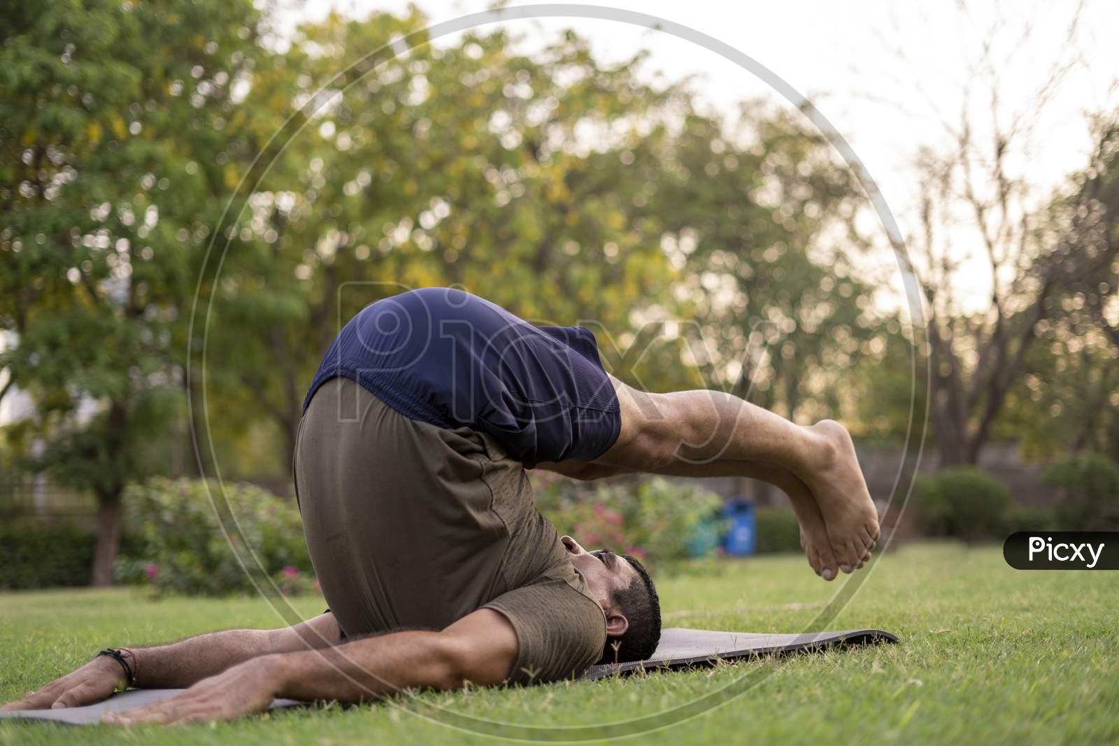Mid-Aged Man Doing Yoga In A Park Covered With Trees