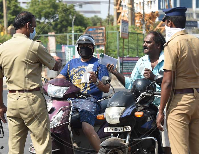 Commuters wait as a police personnel checks for valid travel credentials after a lockdown was reimposed as a preventive measure against the spread of the COVID-19 coronavirus, in Chennai on June 19, 2020.