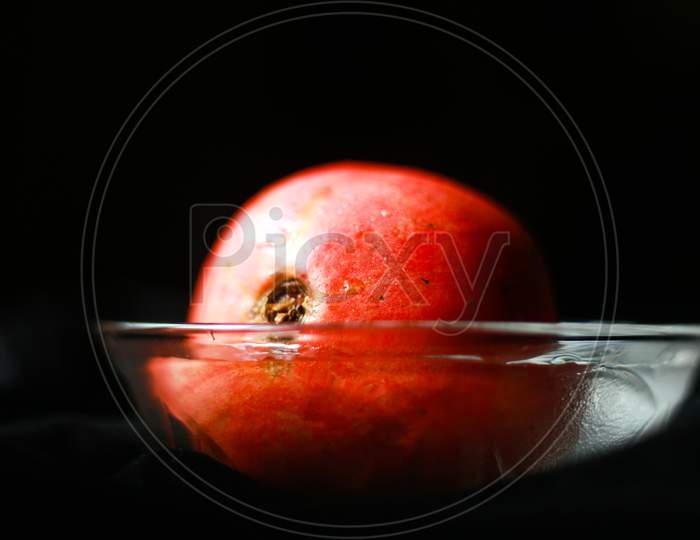Pomegranate in transparent bowl with dark background