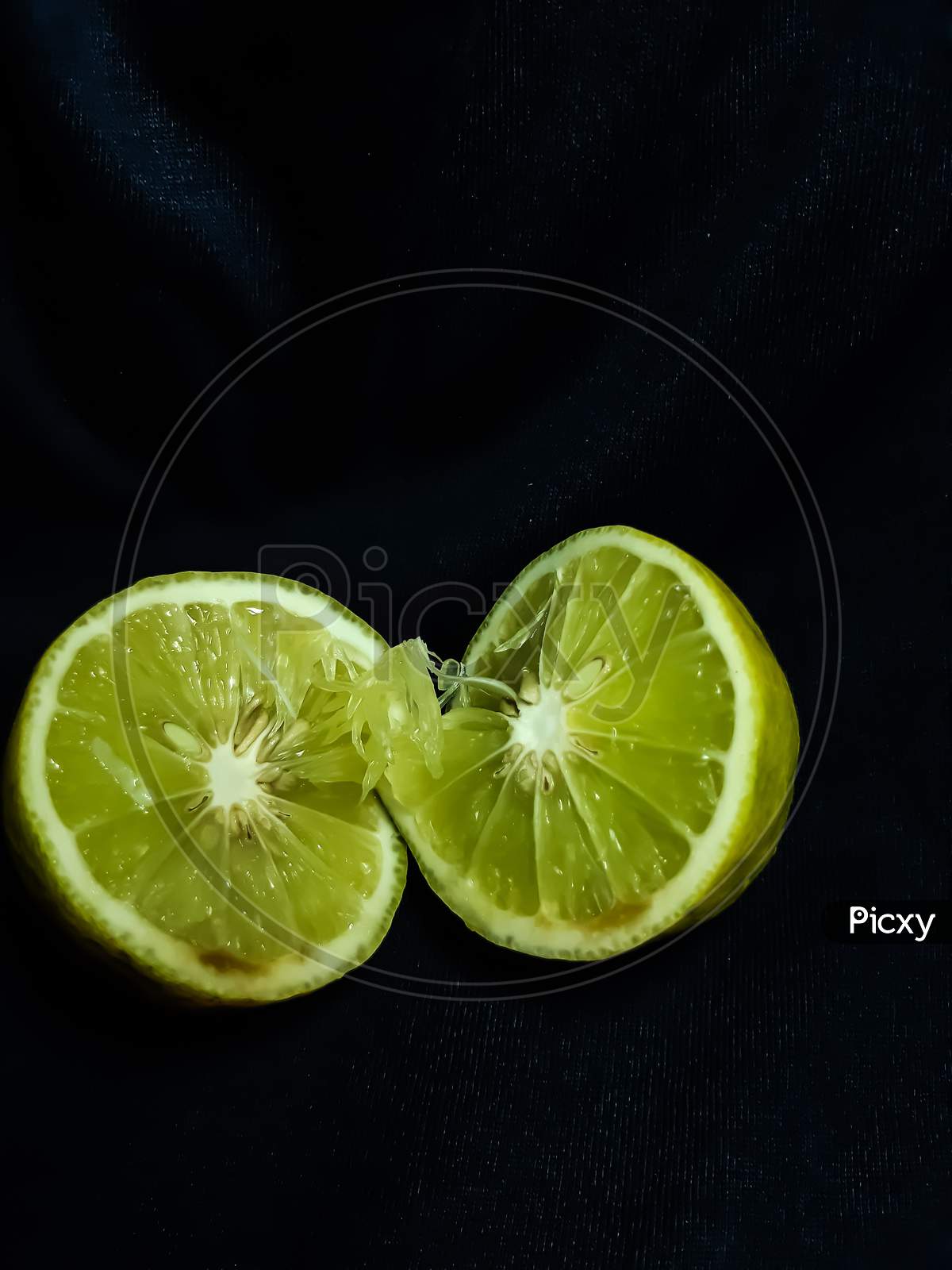 A Lemon Is Cut In The Middle And It Is On A Black Background.