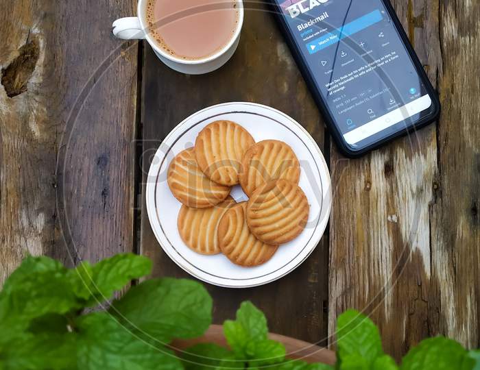 Tea cup with biscuits on an wooden table with Amazon movie