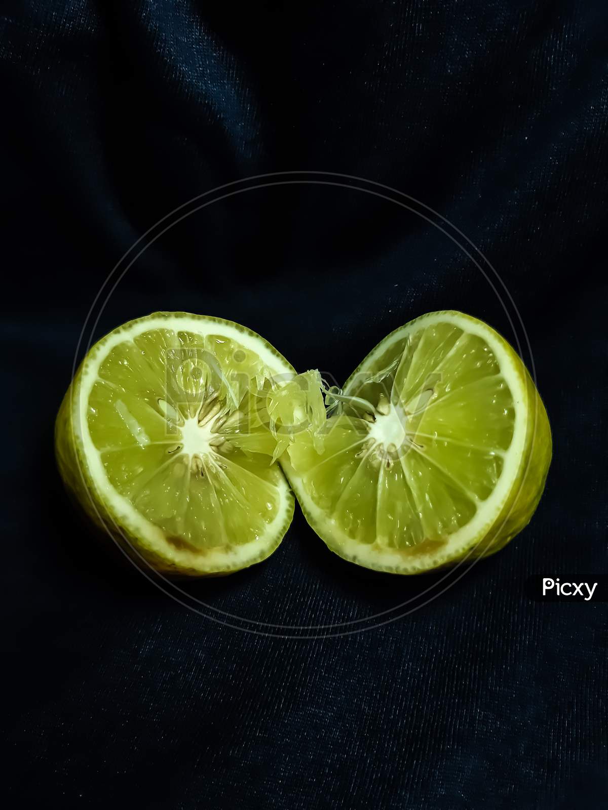 A Lemon Is Cut In The Middle And It Is On A Black Background
