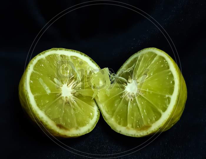 A Lemon Is Cut In The Middle And It Is On A Black Background