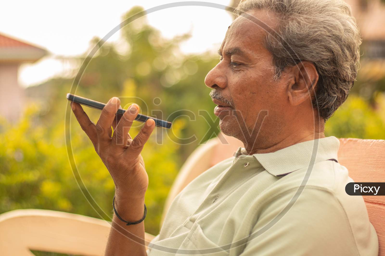 Senior Man Using Virtual Assistant In Phone - Indian Elder Man Using Voice Command On Mobile - Old Man Talking On Smartphone At Outdoor.