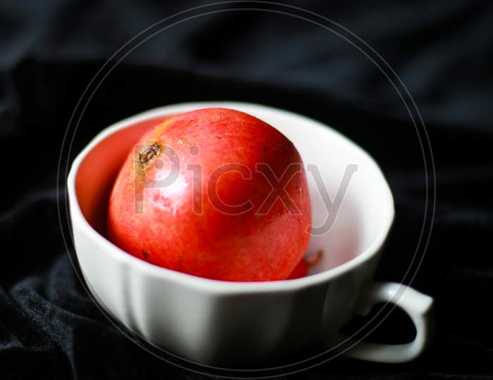 pomegranate in a white bowl with black cloth