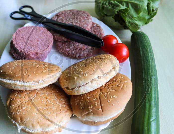 Homemade making of a grilled burger with tomatoes and salad on a plate.