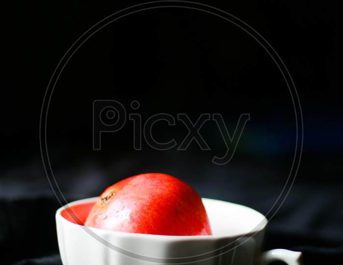 pomegranate in a white bowl with black cloth