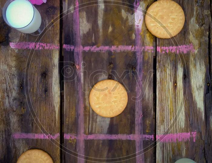 Tic Tac Toe game with milk and Biscuits on an wooden table