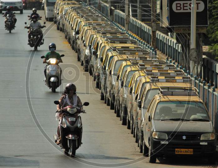 People ride past parked taxis during the nationwide lockdown to limit the spreading of coronavirus disease (COVID-19) in Mumbai, India on April 20, 2020.