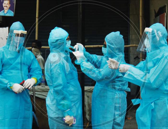 Healthcare workers wearing protective suits help each other to wear a mask before going to visit a slum area at Worli to test the residents for coronavirus during the nationwide lockdown to limit the spreading of coronavirus disease (COVID-19) in Mumbai, India on April 20, 2020.