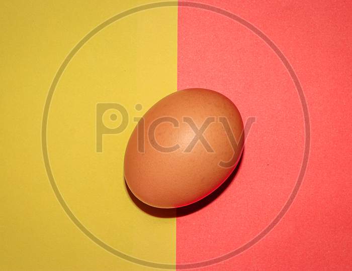 Brown colour egg on yellow red two colour background . Top view.