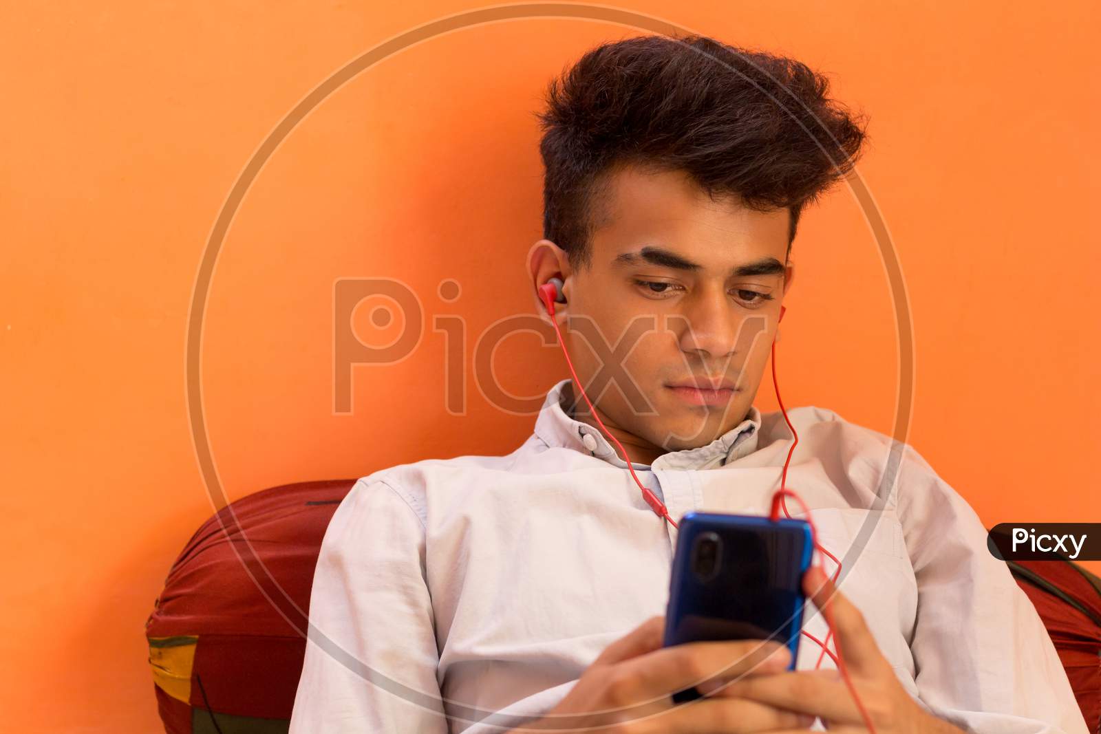 A Young Man Listening To Music On His Cellphone