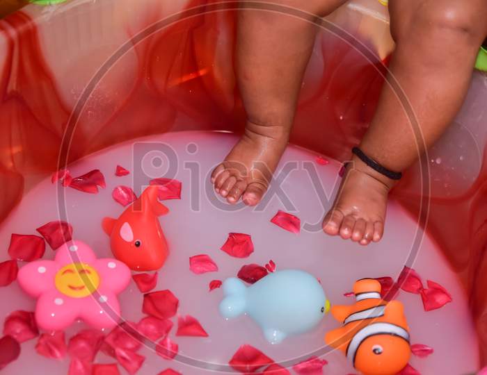 Legs of a newborn in closeup. Baby's feet and copy space. Infant care and colic. Playing in water.